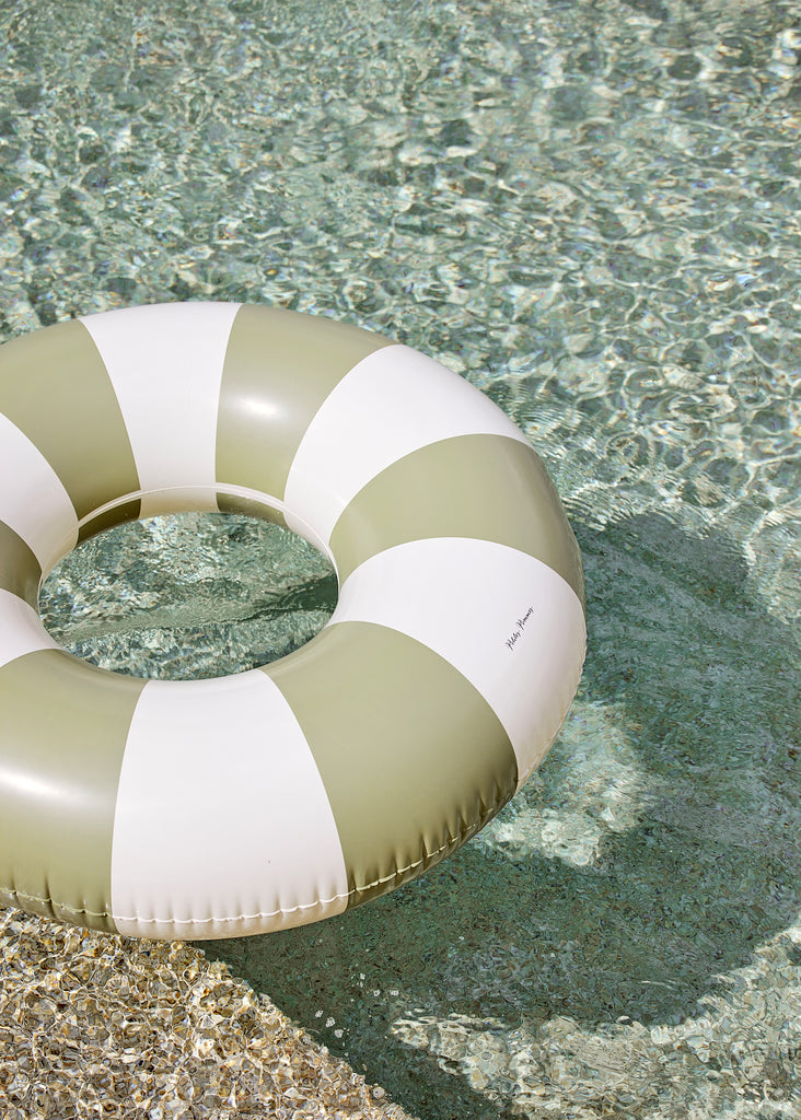 Petites Pommes Terra Verde Pool Float close up in pool. It is a striped pool ring in olive green and cream for adults.