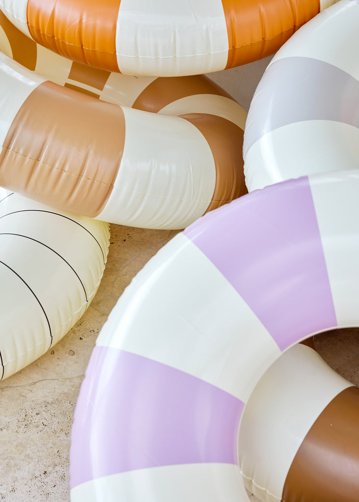 Petites Pommes Violet Pool Float close up. It is a striped pool ring in violet and cream for adults.